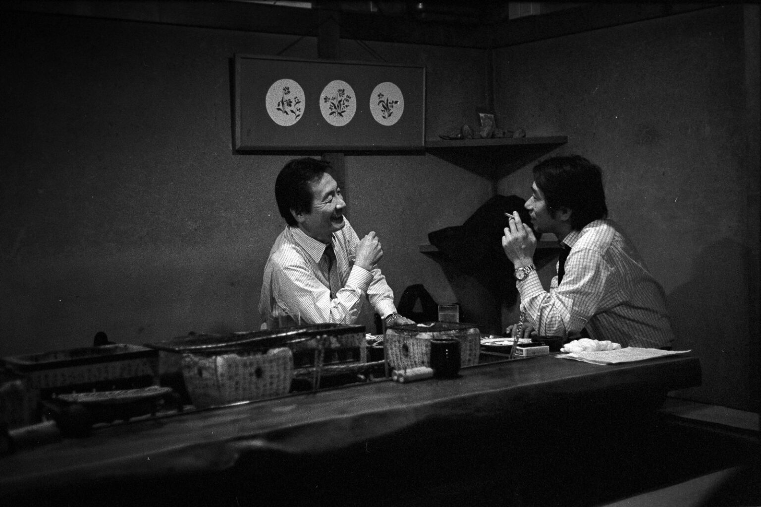 Izakaya Business by Joel Aron, a black and white photograph of two people talking at a Tokyo food counter